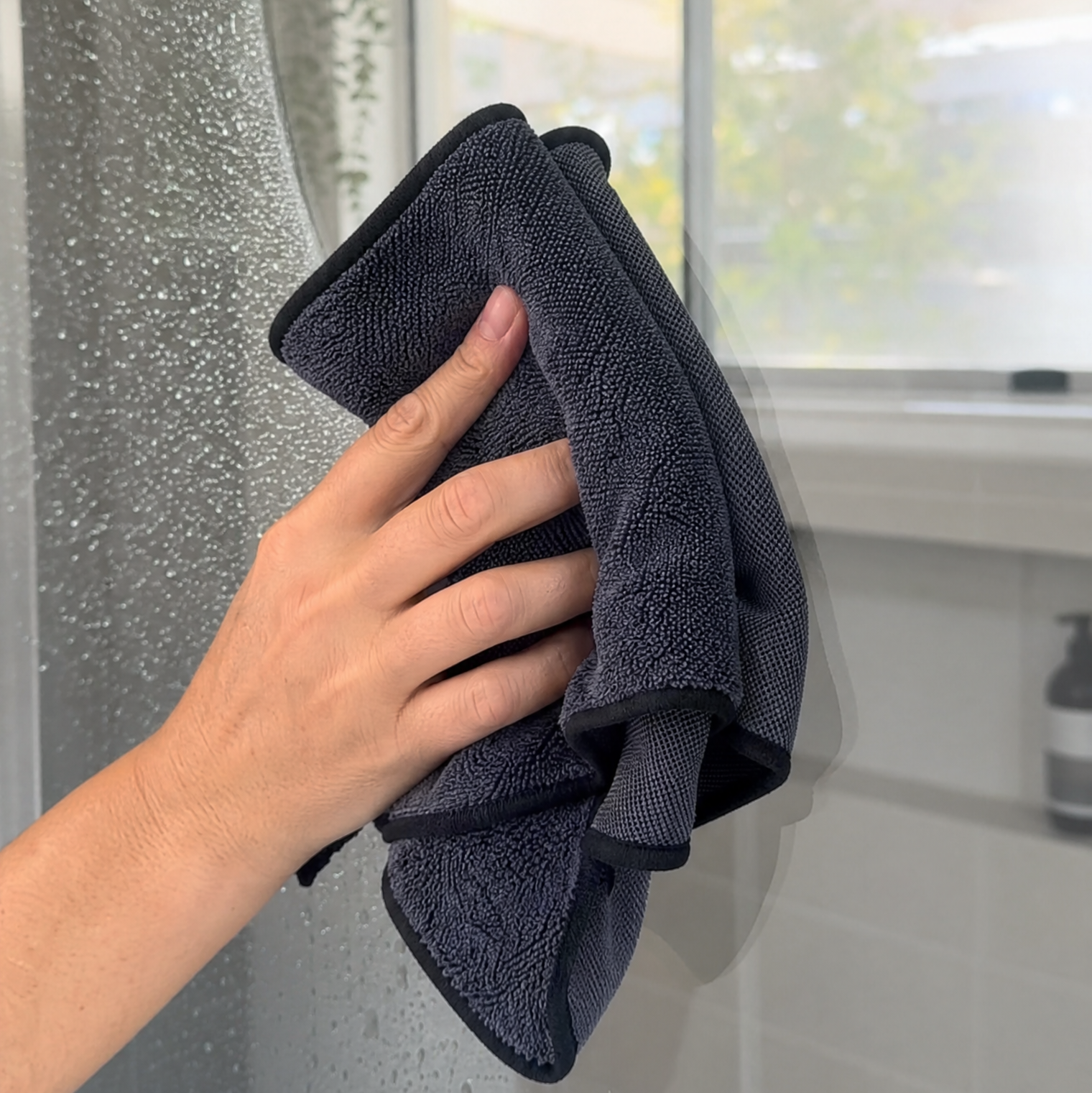 Wiping a glass shower screen streak-free with the Microfibre Cleaning Cloth